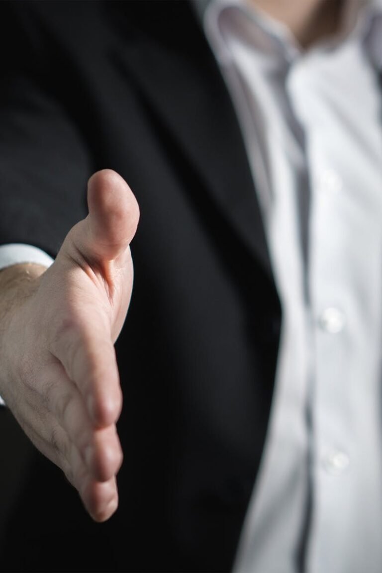 Close-up of a businessman extending hand for a handshake, symbolizing agreement and partnership.